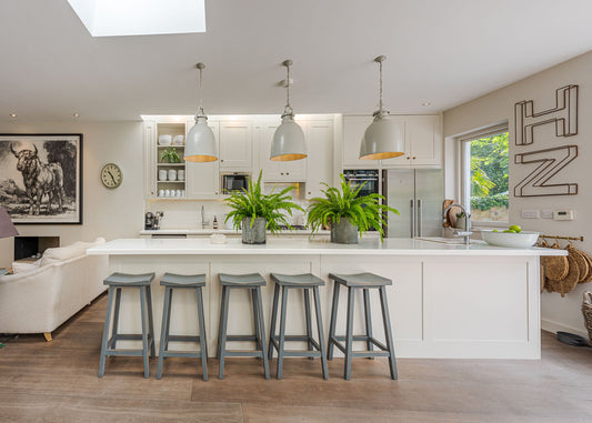Modern kitchen with white island, gray stools, and decorative elements.