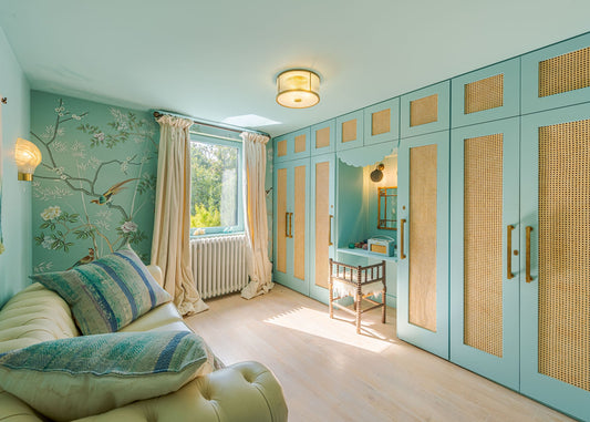 Modern bedroom with blue mint walls, a large wardrobe, and a sofa with decorative pillows.