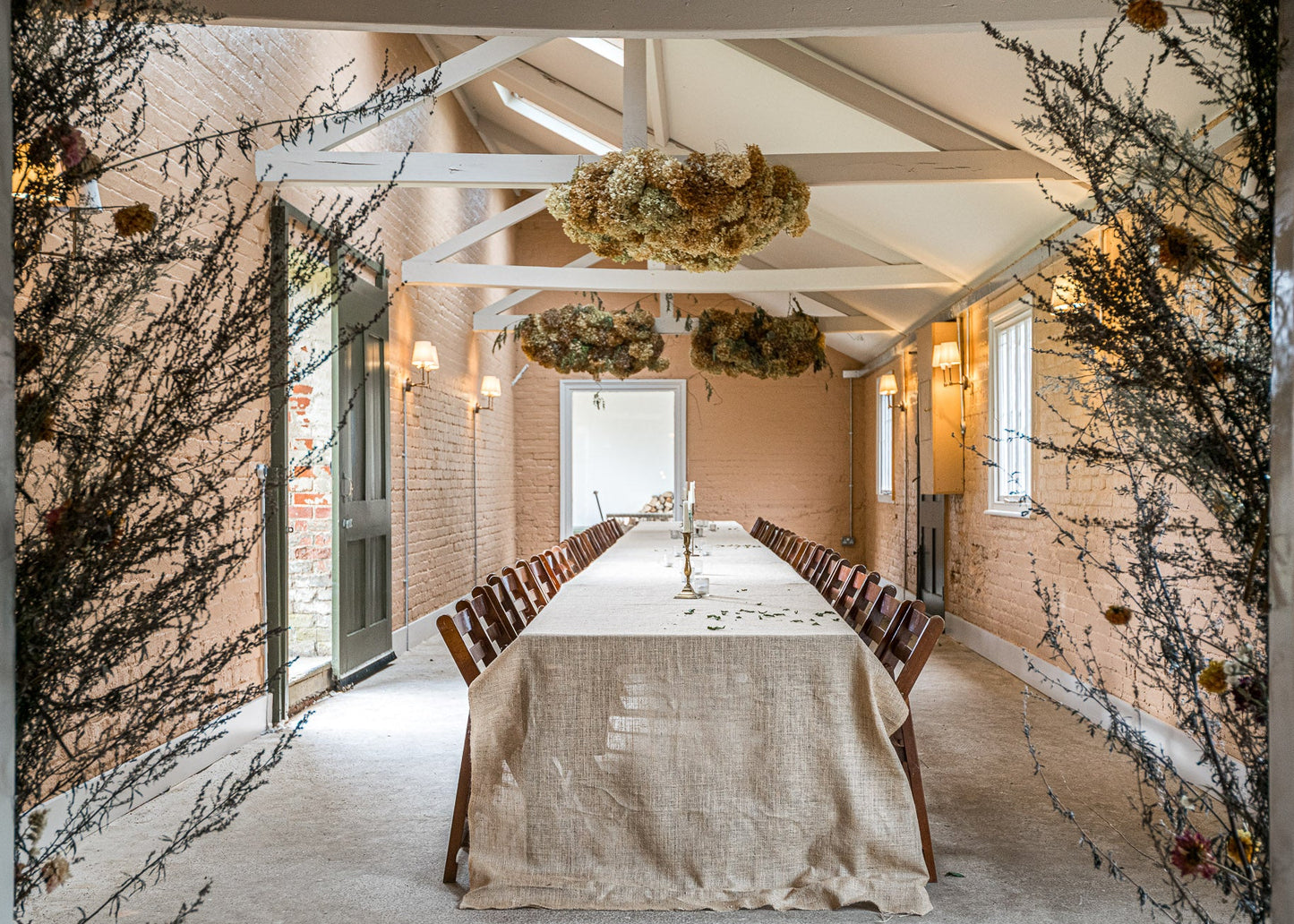 Dining room with long table set for a meal, decorated with plants and natural light.