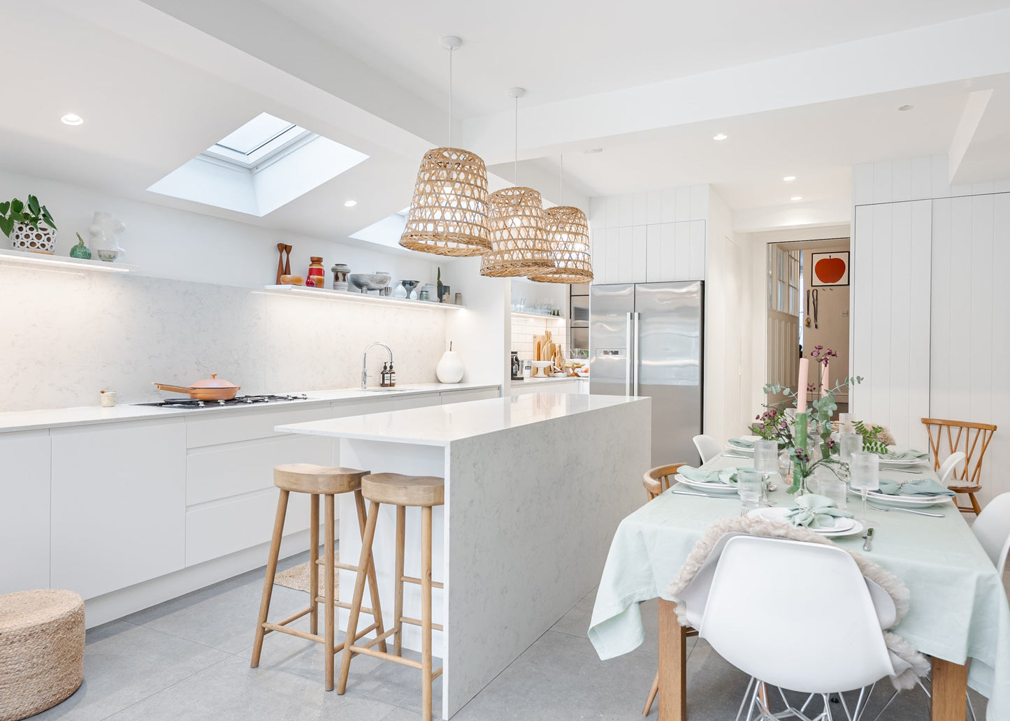 Modern kitchen with white island, stools, and dining table set.